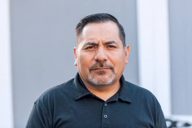Offerings hispanic mature man posing looking at the camera at his home backyard